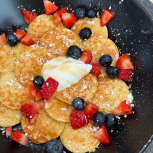 mini dutch pancakes topped with berries, powdered sugar, and yogurt